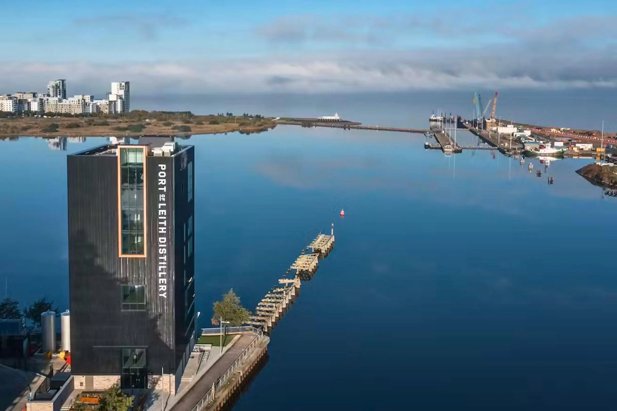The exterior of the modern vertical Port of Leith Distillery building against the Edinburgh skyline
